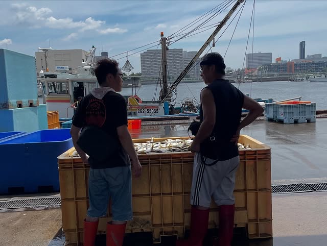 店主と漁師が魚を前に話し合っている写真。改善を重ねるやりとりが伝わるもの