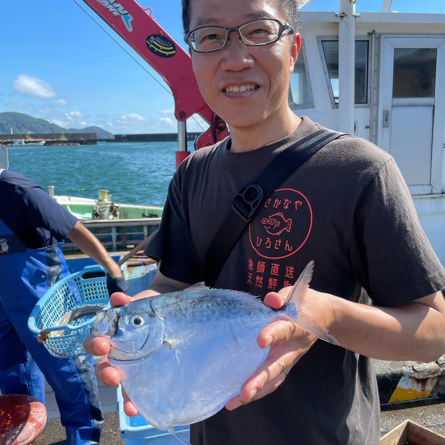 店頭に並ぶ魚と、その奥で作業する店主の写真。魚と人のつながりが伝わる構図