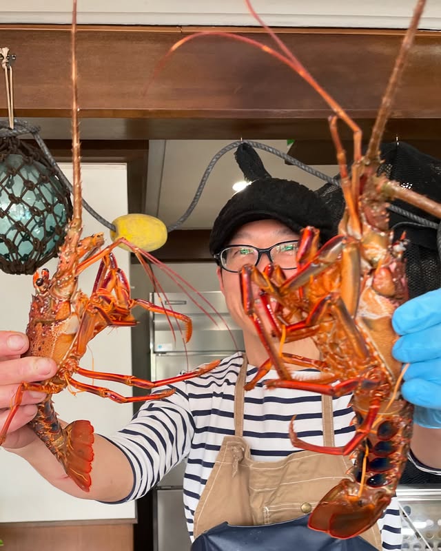 漁師から届いた魚を店主が受け取り、状態を確認している写真